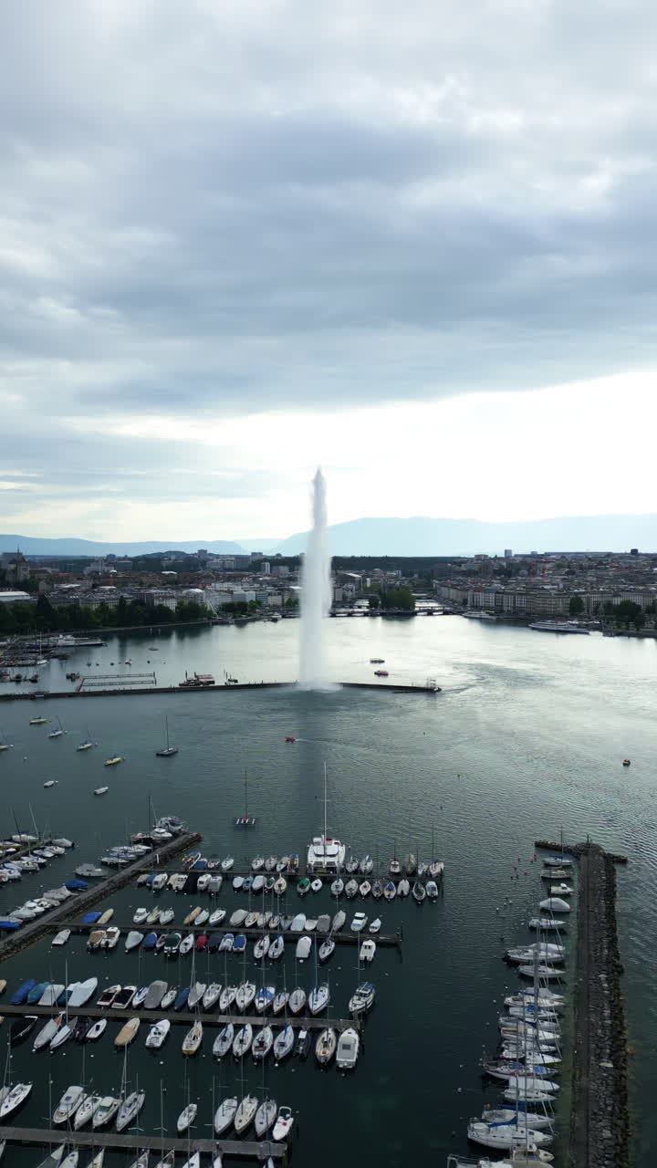 Vertical, aerial: water fountain of Geneva during the day (Rade of Geneva) in canton of Geneva, Switzerland, orbit drone shot