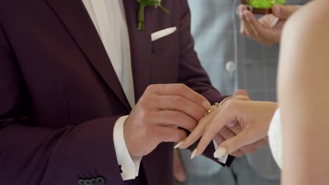 Wedding-ceremony,-groom-placing-the-ring-on-the-bride’s-finger-at-the-altar-in-the-church