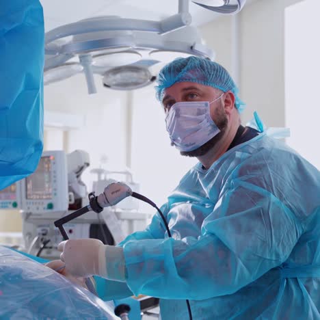 male specialist in mask performing a surgery in clinic. professional doctor in medical uniform doing a surgery on kidneys in the modern operating room.