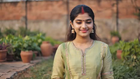 beautiful young indian woman wearing traditional clothing and jewelry, smiling serenely in a peaceful garden with terracotta pots and lush plants, enjoying a moment of tranquility