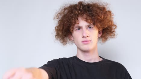 closeup of the face of a curly redhaired boy a student on a light brown background closeup of the face of a curly redhaired boy a student on a light brown background the emotion of peace happiness relaxation meditation a guy with narrowed eyes