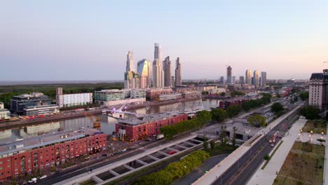 Dolly-In-Luftaufnahme-Der-Docks-Von-Puerto-Madero-Mit-Luxusrestaurants-Und-Der-Puente-De-La-Mujer,-Exklusive-Wolkenkratzer-Im-Hintergrund,-Epischer-Sonnenuntergang