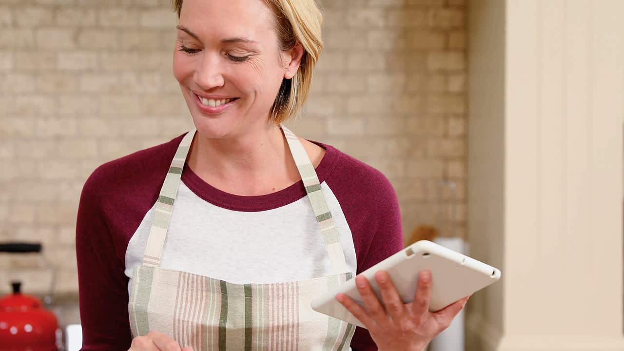 mujer joven sonriente usando su tableta en la cocina 4k 4k