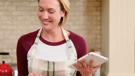 Smiling-young-woman-using-her-tablet-in-the-kitchen-4K-4k