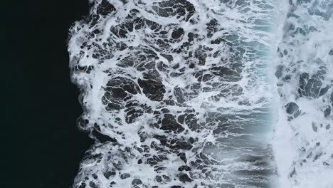 slow motion aerial view of the sea waves breaking on the shore