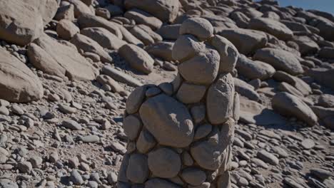 small stones forming a figure, standing gracefully in a rocky landscape beneath a clear blue sky, creating a serene and artistic atmosphere that embodies natural beauty and tranquility