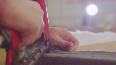 Close-up-of-a-worker's-hands-stapling-upholstery-on-a-boxspring-bed-in-a-bright-factory