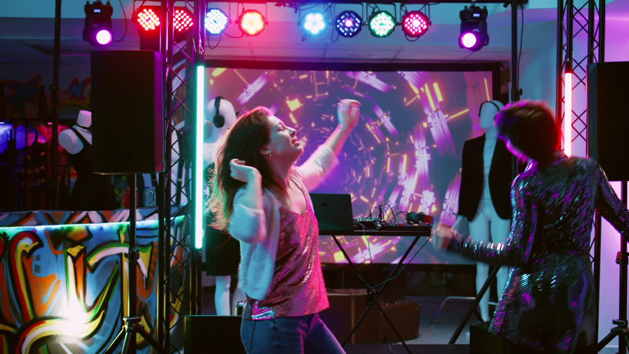 Women dancing at a nightclub disco party with a DJ and colorful lights