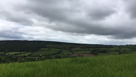 Ein-Niedriger-Zeitraffer-Von-Dunklen-Wolken,-Die-über-Schöne-Grüne-Felder-Rollen