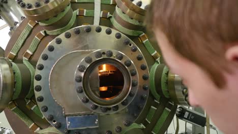 scientist observing a high-temperature process in a vacuum chamber