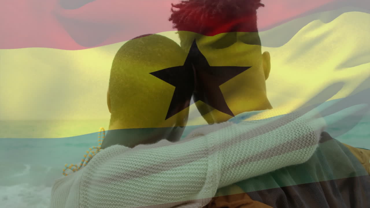 Coppia che si abbraccia in riva all'oceano, con sovrapposizione animata della bandiera del Ghana sullo sfondo.