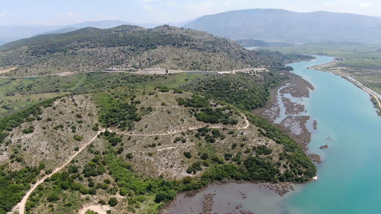 vista de avión no tripulado en albania volando sobre un amplio río y un paisaje verde junto al mar con montañas en la parte posterior