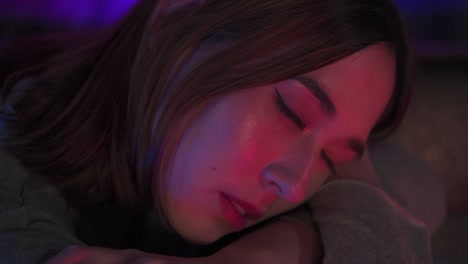 retrato en 4k de la soledad de una mujer asiática sentada en un club nocturno con luces de neón iluminadas
