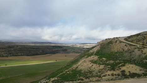 lateral drone flight over the top of a hill where the remains of a tower and a section of the wall of a 14th century castle appear