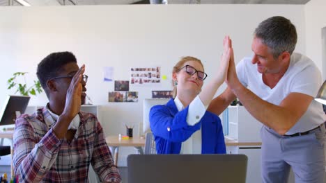 Multi-ethnic-business-colleagues-discussing-over-laptop-in-modern-office-4k