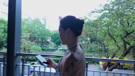 woman using phone on balcony with city view