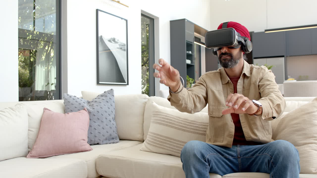 Usando un visore VR, uomo seduto sul divano che sperimenta un gioco di realtà virtuale.