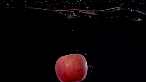 vibrant red apple being dropped into water in slow motion