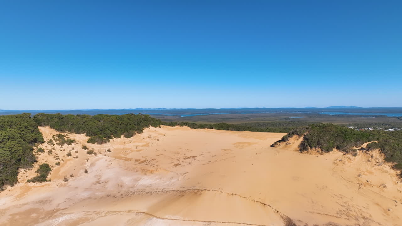 Aerial flies across Rainbow Beach's famed Carlo Sand Blow nestled within the rich forest of the Great Sandy National Park. Clear fine and calm day at the Fraser Coast Queensland Australia.