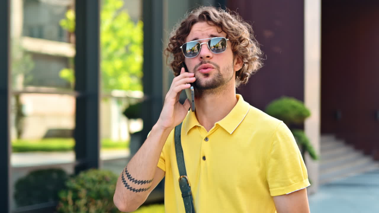 Man in yellow shirt talking on the phone while walking on the street