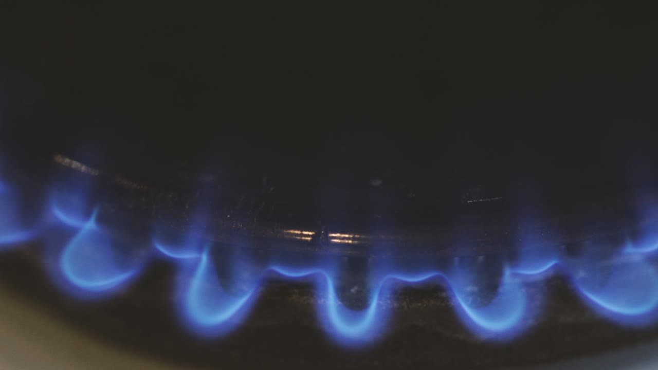 오래된 전통적인 가스 스토브를 비추는 불타는 매치를 가진 세부 사항.