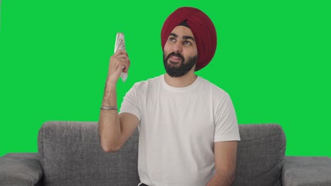 hombre indio sikh feliz usando el dinero como pantalla verde del ventilador