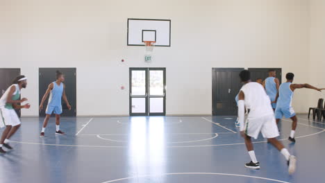 Multiracial male basketball players playing basketball, passing and throwing basketball in gym