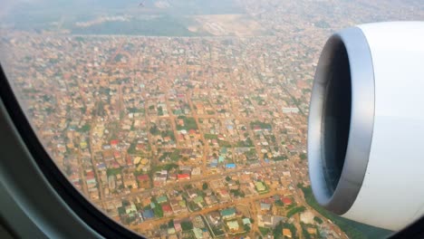 View-through-airplane-window-over-the-city-during-landing-on-cloudy-day