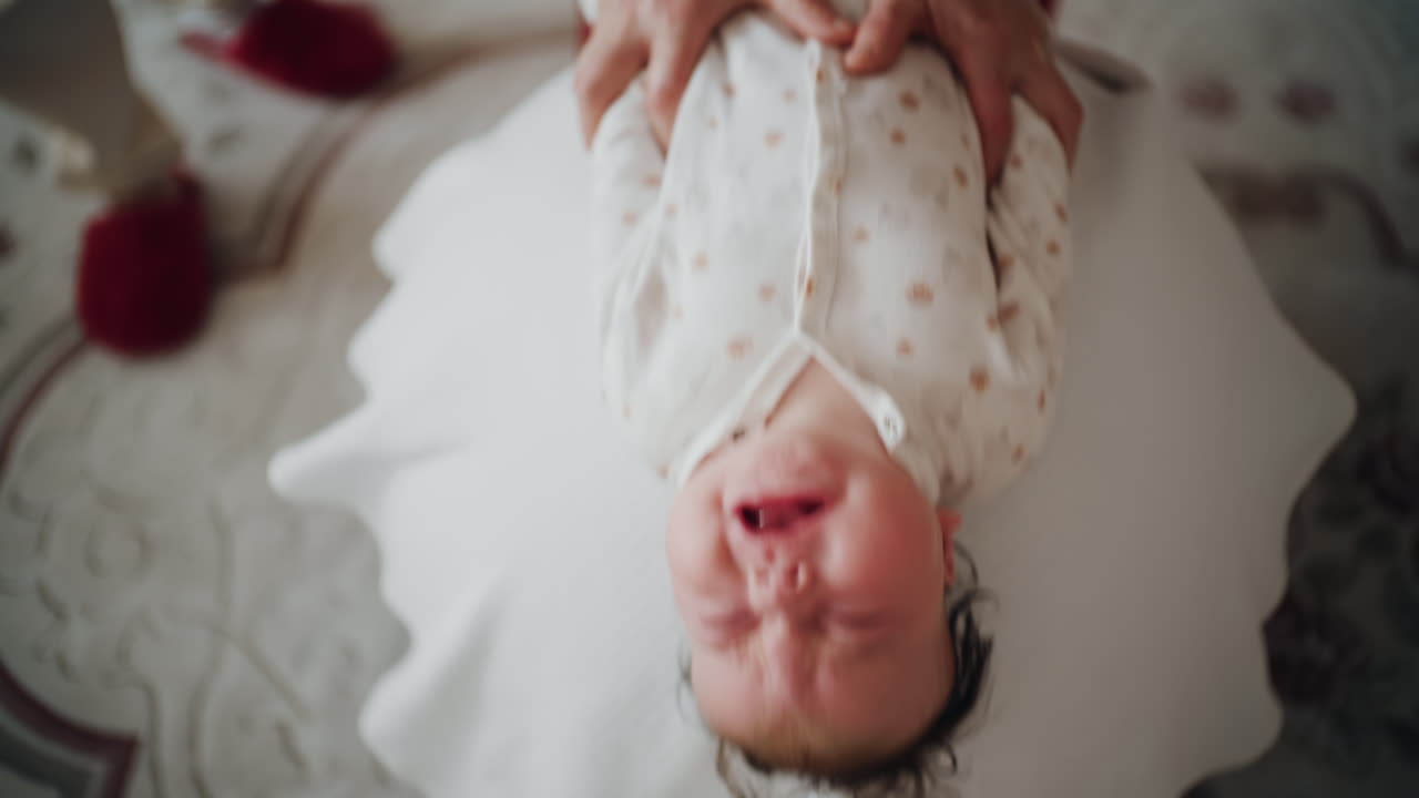 Baby placed on the back on a stability ball while adults support the infant's torso and shoulders