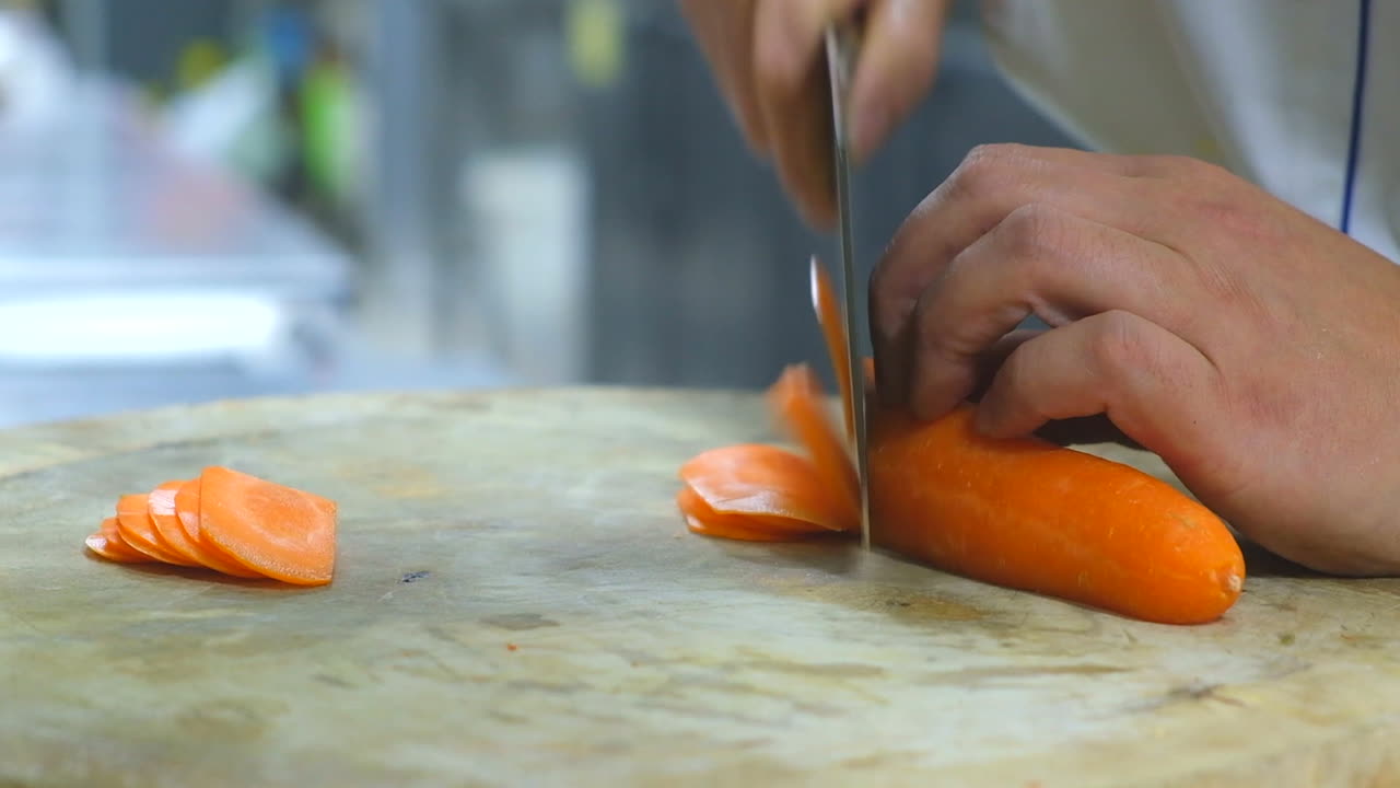 Person slicing a carrot on a wooden cutting board