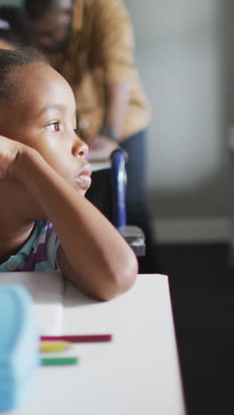 video de una niña afroamericana pensativa sentada en un escritorio en el aula