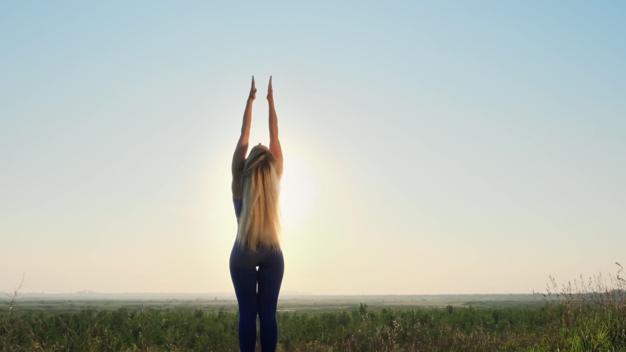 Woman practicing yoga outdoors at sunrise/sunset