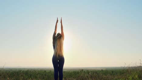 woman practicing yoga outdoors at sunrise/sunset