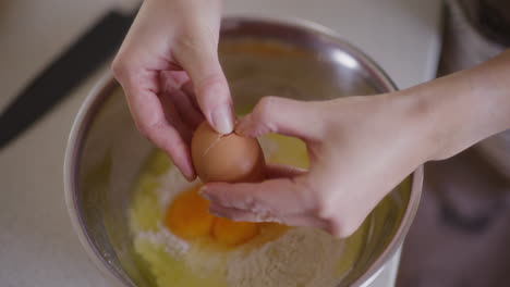 close-up of cracking raw egg into bowl breaking egg with knife