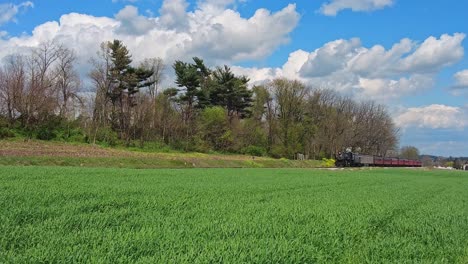 View-of-a-Steam-Passenger-Train-Approaching-Blowing-Smoke-and-Steam-on-a-Beautiful-Spring-Day