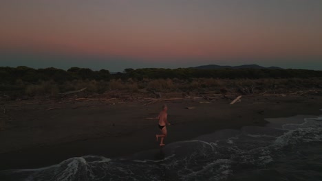 One-senior-man-running-jogging-at-a-sandy-beach-at-sea-sunset-doing-active-sport-fitness-training-for-marathon-and-triathlon-and-a-healthy-body,-muscles-and-endurance