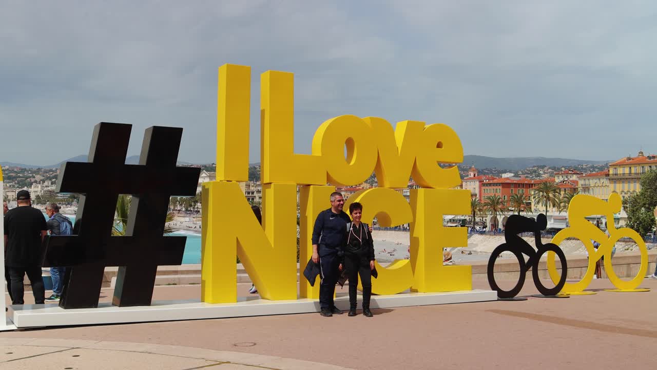 Tourists by famous #I Love Nice sign with cityscape in background