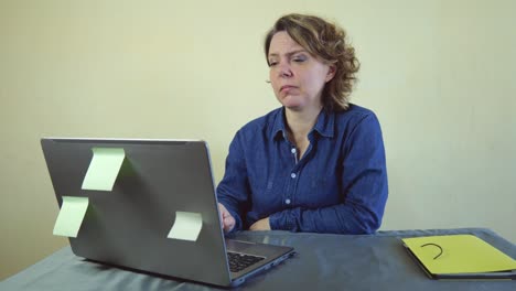 a forty-year-old woman in a blue shirt works at a laptop. freelancer adult woman