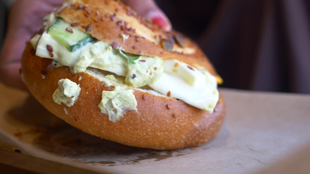 cerca de un delicioso sándwich de bagel con queso con crema, pepino y aguacate