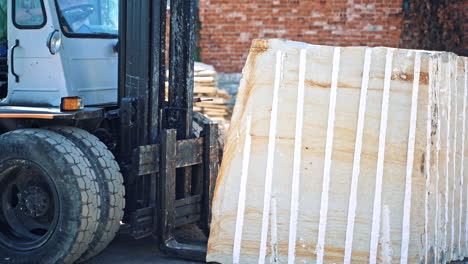Forklift truck loading marble. Forklift carrying large piece of marble in quarry