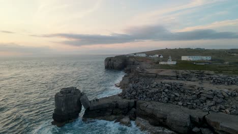 4K-footage-of-a-drone-standing-still-during-the-sunset-over-the-ocean,-facing-the-cliffs-of-Portland-Bill,-Dorset-in-England