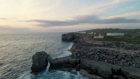 4k footage of a drone standing still during the sunset over the ocean, facing the cliffs of portland bill, dorset in england