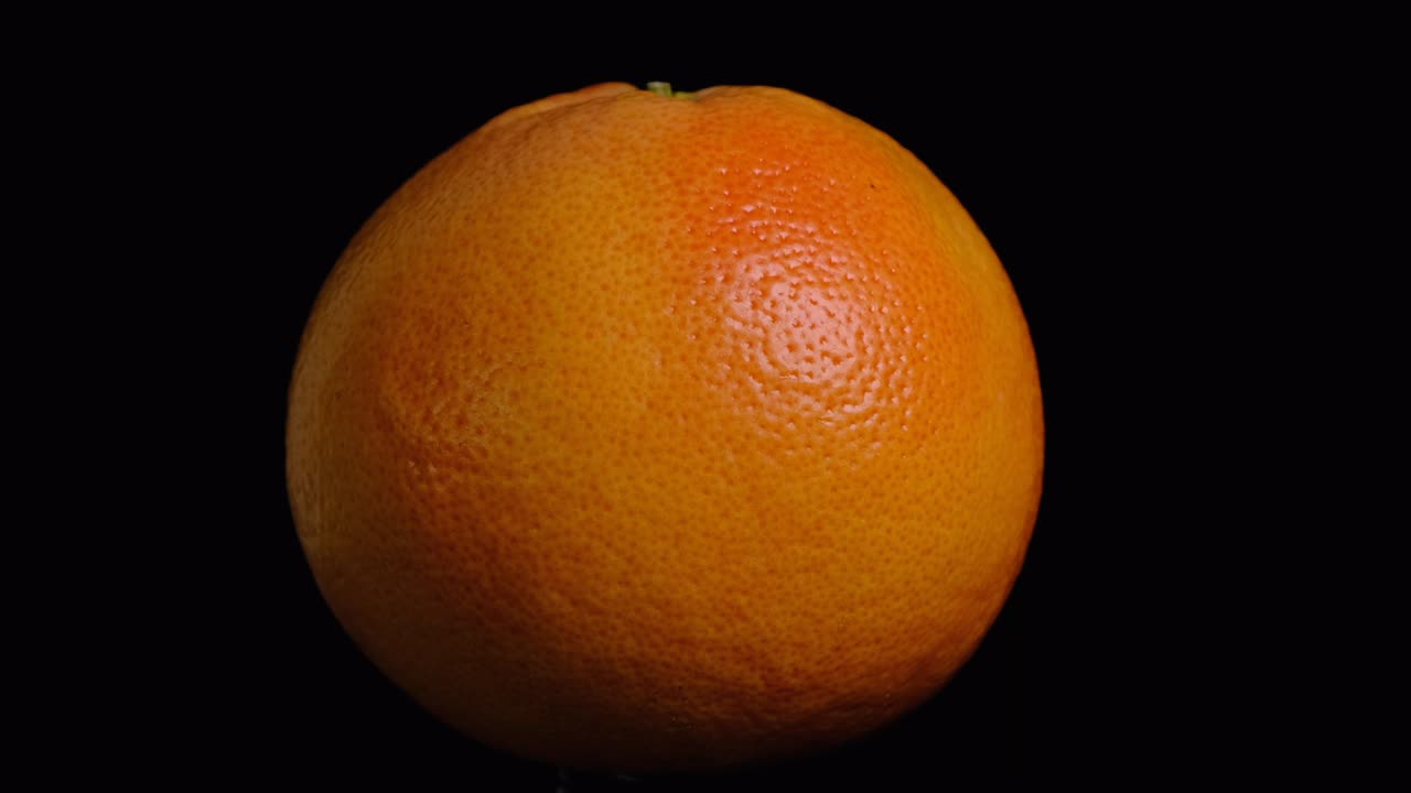 toronja entera giratoria sobre un fondo negro