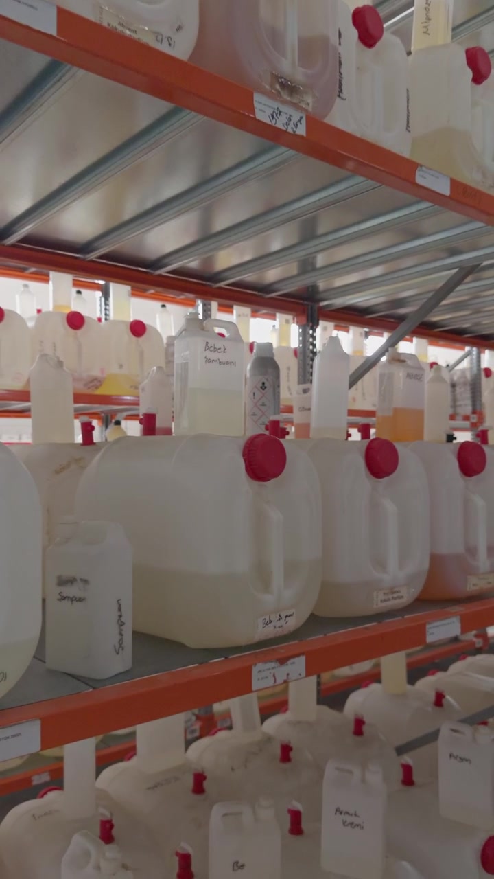 Large plastic jugs containing liquid chemicals with warning labels neatly arranged on industrial warehouse storage shelves