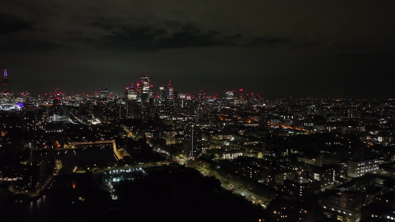 Panorâmica aérea do distrito de Shadwell, com o horizonte da cidade de Londres ao fundo à noite