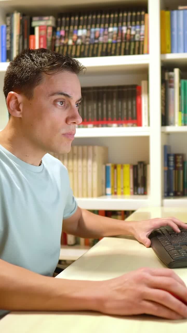 Man working on computer in front of bookshelf