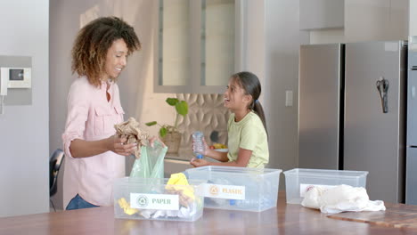 Feliz-Madre-E-Hija-Birracial-Clasificando-Basura-Para-Reciclar-En-La-Cocina,-Espacio-Para-Copiar,-Cámara-Lenta