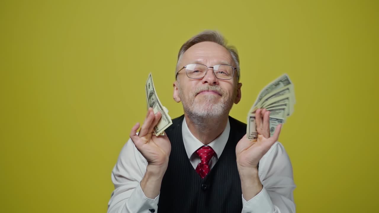 Happy senior man enjoys money. Portrait of an old businessman with many dollar banknotes in his hands. Great business deal.