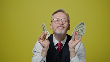 happy senior man enjoys money. portrait of an old businessman with many dollar banknotes in his hands. great business deal.