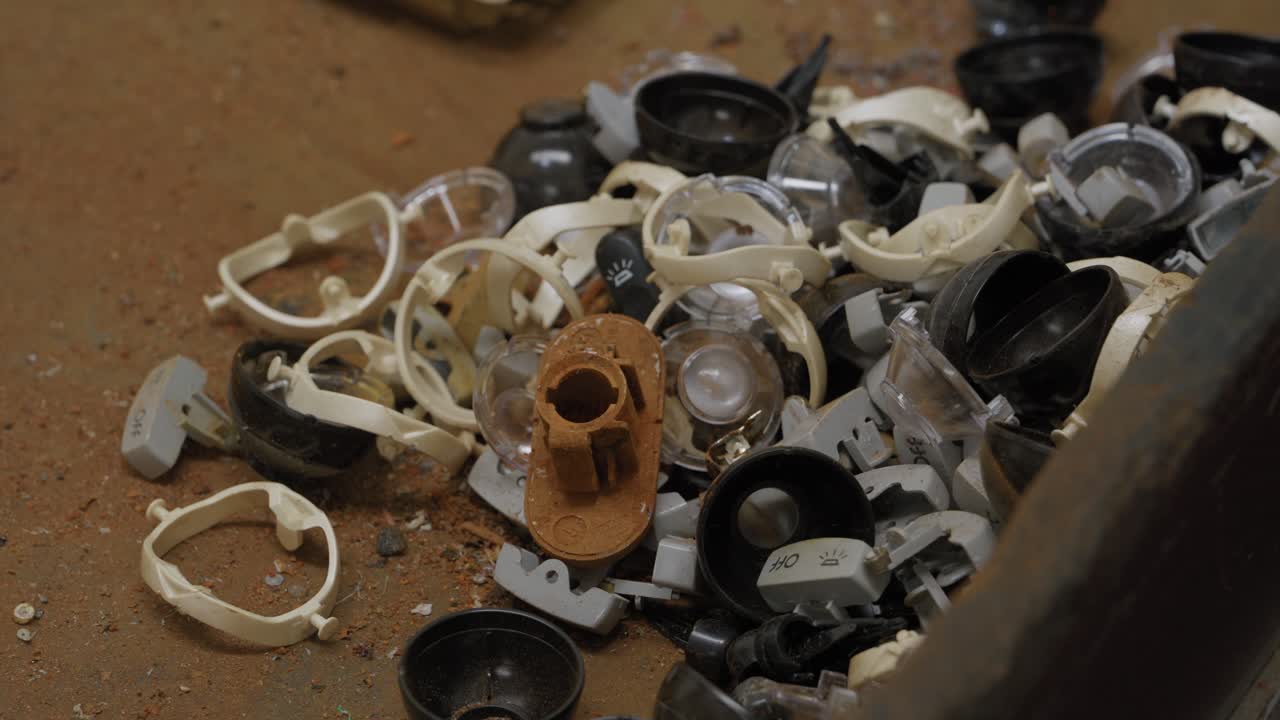 Pila di manopole di plastica scartate e parti di interruttori della luce in un bidone per il riciclo.
